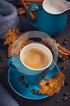 Blue cup of coffee with coffee beans and autumnal dry leaves