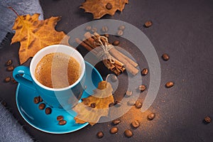 Blue cup of coffee with coffee beans and autumnal dry leaves