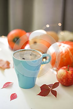 Blue cup of coffee with orange pumpkins in background