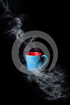 Blue Cup of hot coffee surrounded in steam black background