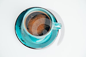 Blue cup o black coffee with a saucer on a white table. Top view, close-up