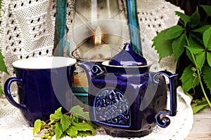 Blue cup and teapot stand on a white tablecloth against the background of a vintage lantern