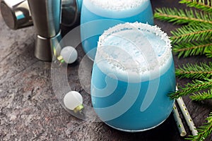 Blue curacao Christmas Cocktail, garnished with coconut on Christmas decorated holiday table with Christmas ornaments. Holiday