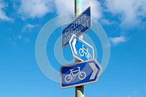 Blue cycling signs on a post point directions