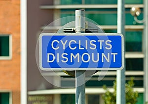 Blue cyclists dismount sign