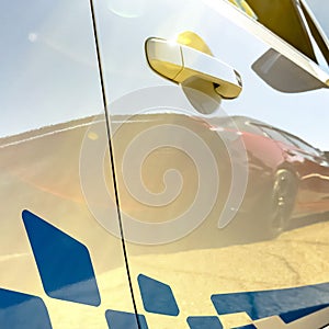 Blue decal on a sunlit white car with reflections