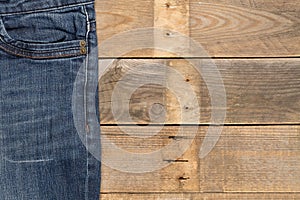 Blue denim cotton fabric trousers on brown wooden table with copy space - flat lay top view