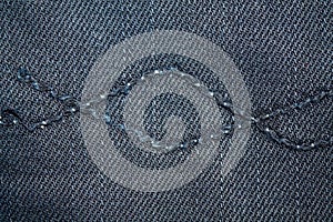 Blue denim macro texture with seam for jeans background