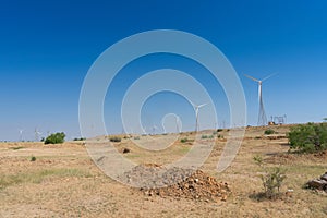 Blue desert sky and Electrical power generating wind mills producing alterative eco friendly green energy for consumption by local