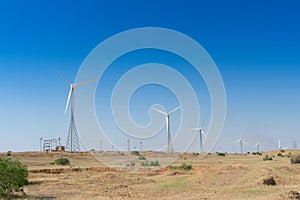 Blue desert sky and Electrical power generating wind mills producing alterative eco friendly green energy for consumption by local