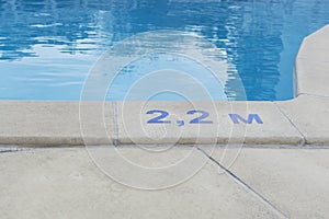 Blue digits and letter as sign of depth in meters in swimming pool, deep pool with blue water, no people around,