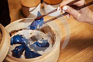 Blue Dim Sum chinese cuisine in bamboo steamer and pot. Top view fresh dumplings with hot steams on wood plate with