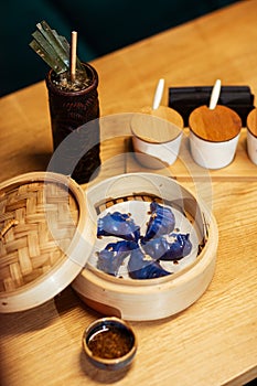 Blue Dim Sum chinese cuisine in bamboo steamer and pot. Top view fresh dumplings with hot steams on wood plate with