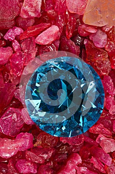 blue dimond placed on a pile of raw granit gemstones