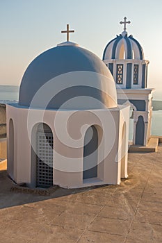 Blue dome and a bell tower of a church at sunset, Imerovigli village, Santorini island