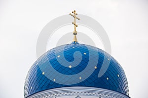 Blue dome of the Christian Church with stars and gold crosses close-up.