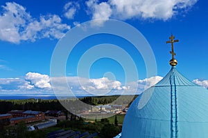 A blue dome with a golden cross of the Valaam Monastery of the Savior Transfiguration on a clear sky background close-up