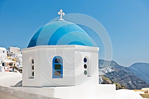 Blue dome of a white church with Caldera cliff in a background, Oia village, Santorini island