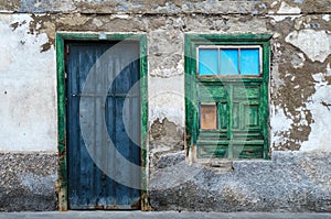 A blue door and a green window, facade of an old house
