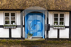 Blue door on old country house with thatched straw roof in Denmark