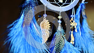 Blue dream catcher hanging on dark background close up with suspension wing