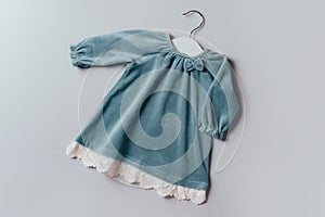 Blue dress for baby girl with white hanger on grey background. Set of baby clothes and accessories for birthday party