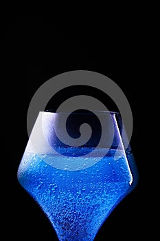 Blue drink is poured into a glass. Black background