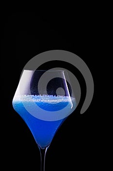 Blue drink is poured into a glass. Black background