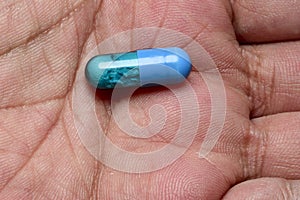 Blue drug pill in the palm of the hand