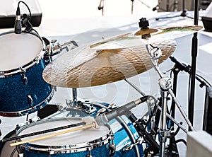 blue drum set with two wooden drumsticks on it. musical instruments on stage ready for the gig.