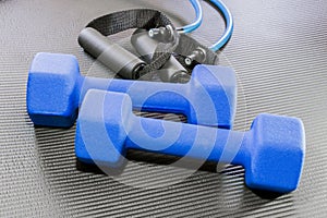 Blue dumbbell weights and resistance bands lying on a black yoga