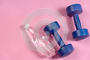 Blue dumbells on the pink yoga matt