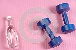 Blue dumbells on the pink yoga matt