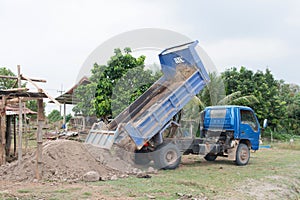 Blue dump truck unloading soil at construction site