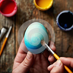 blue easter egg in hands with brush