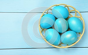 Blue Easter eggs in a basket on a blue background.