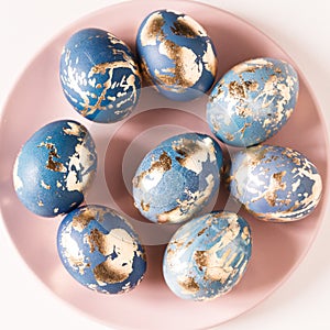 Blue easter eggs decorated gold patel on the pink plate photo