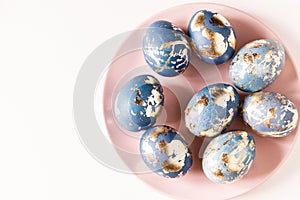 Blue easter eggs decorated gold patel on the pink plate. Free space for text photo