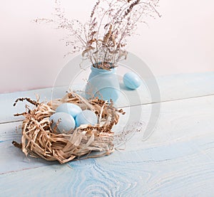 Blue Easter eggs in nest on wooden background.