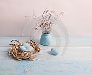 Blue Easter eggs in nest on wooden background.