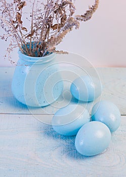 Blue Easter eggs in nest on wooden background.