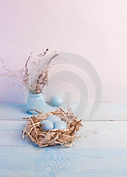 Blue Easter eggs in nest on wooden background.