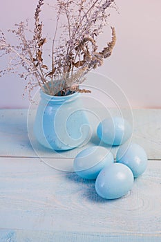 Blue Easter eggs in nest on wooden background.