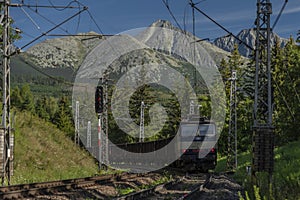 Blue electric cargo train under Vysoke Tatry mountains in summer morning