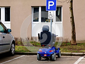 Blue electric disability or handicap scooter in handicap parking stall. photo
