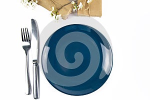 Blue empty plate with fork and knife and gifts decorated with white flowers isolated on white background