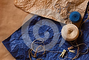 Blue end beige skein of thread, tiny pins on natural brown and blue crumpled blue paper. Design templates with free copy space for