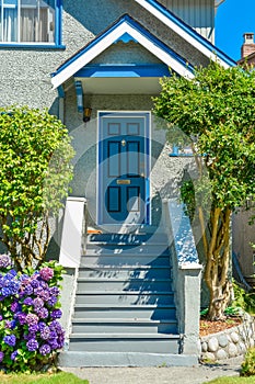 Blue entrance door of family house under the porch with the doorsteps in front