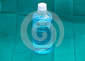 Blue ethyl alcohol liquid in plastic transparent bottle on green photo