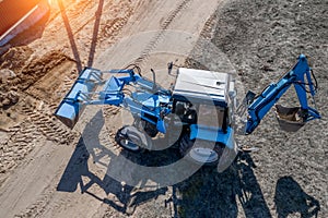 Blue excavator buries a hole top view